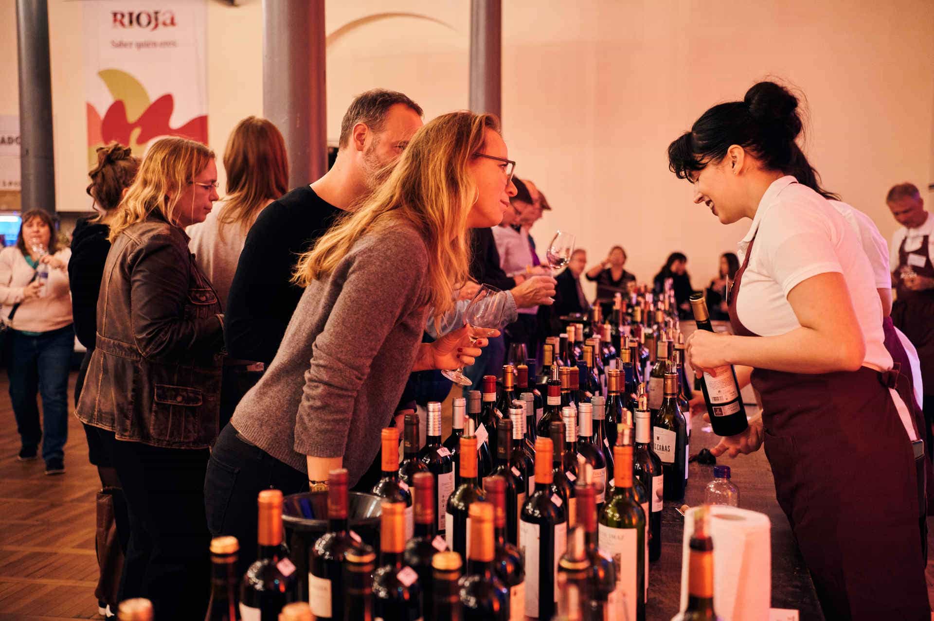 Besucher verkosten verschiedene Weine bei einer Rioja Weinverkostung im Magazin in der Heeresbäckerei. Eine Mitarbeiterin berät die Gäste an einem Tisch mit zahlreichen Weinflaschen